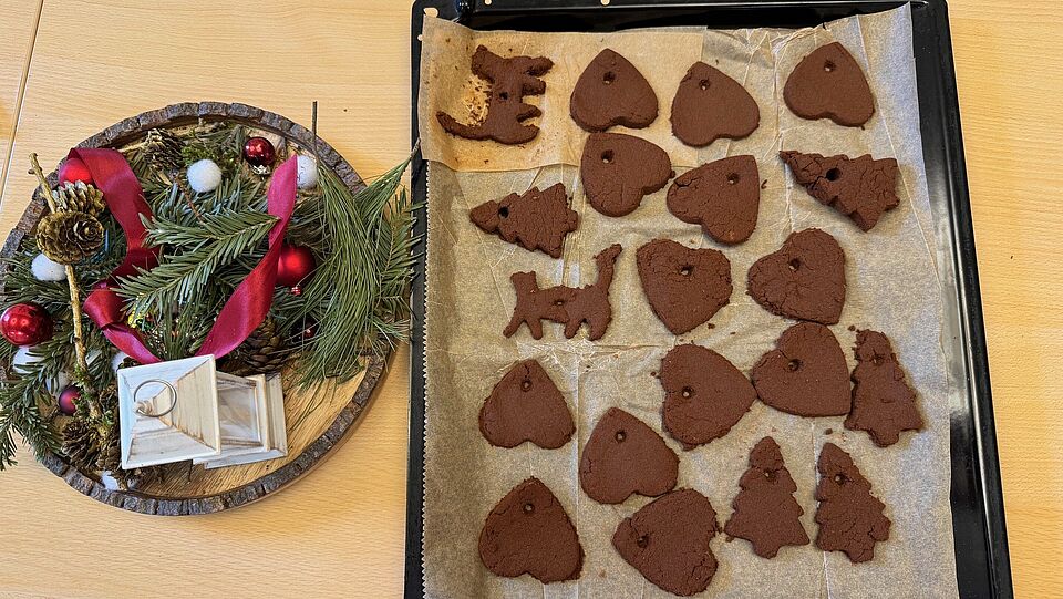 Selbstgebackene Zimtherzen neben Weihnachtsdeko