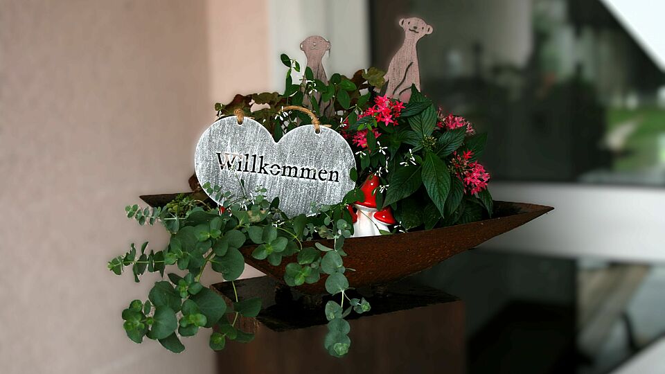 Willkommens-Schild in Herzform in einer Pflanzenschale