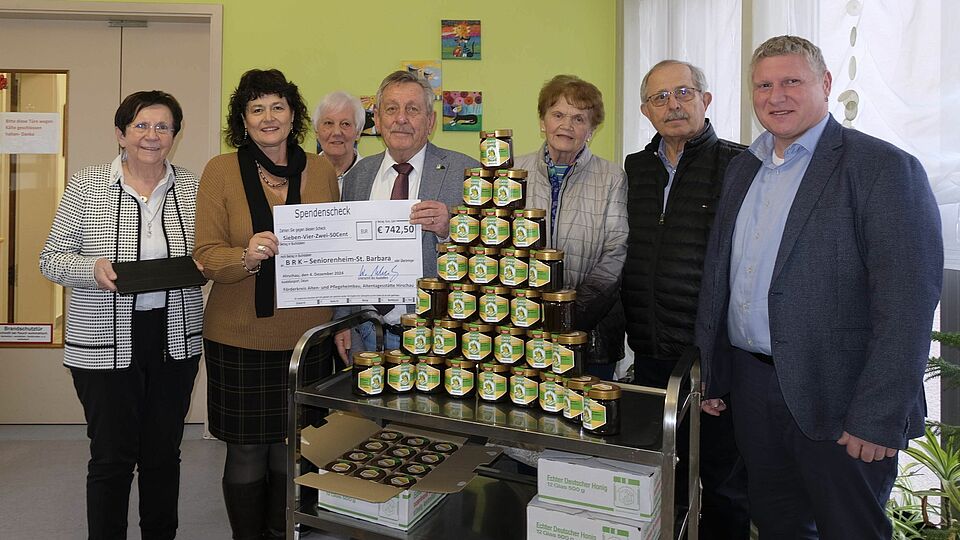 Personen mit Spendencheck neben Honiggläsern