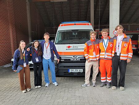 Studenten mit BRK-Ausweis stehen vor einem Rettungswagen